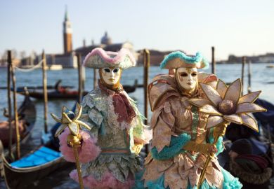 Venice, Veneto, Italy - February 19, 2020 Colourful and beautifully crafted costumes for this couple posing at San Marco square waterfront at sunset.
