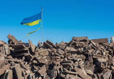 War in ukraine. Destroyed Ukrainian building and damaged flag in the wind
