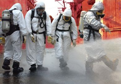 People in protective gear spraying water