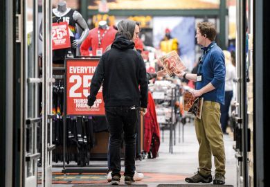 Shopper offered 25% off leaflet in a store entrance to illustrate US colleges get new challenge on tuition fee discounts