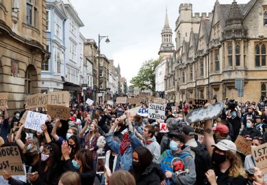 Protestors hold placards and shout slogans during during a protest