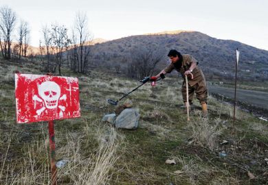 Person walks in a minefield trying to deactivate the devices on the outskirts of the Kurdish town of Halabja, Iraq as a metaphor for ‘Tech without humanities leads to problems’