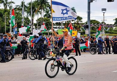 A pro-Israel protestor rides his bike along Biscayne Blvd to illustrate US campuses confront extent of donor influence after Israel rows