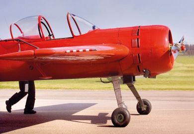 A bright red plane appears to have legs, as a pilot pushes his aircraft A bright red plane appears to have legs, as a pilot pushes his aircraft to illustrate UK funding council budgets set to drop