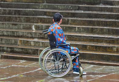 Man in wheelchair looking at steps to illustrate Two-thirds of disabled PhD students poorly supported, says study