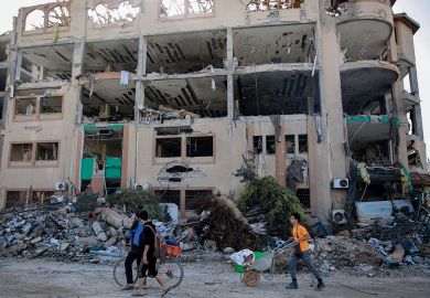 Palestinians walks past the destroyed building of the Islamic University in Gaza City Palestinians walks past the destroyed building of the Islamic University in Gaza City to illustrate Academia in Gaza ‘has been destroyed’ by Israeli ‘educide’
