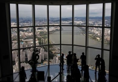 Visitors are silhouetted as they take photographs at the glass-bottomed Seoul Sky observation deck to illustrate UK university explores options in South Korea’s forgotten hub