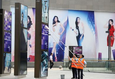 Two workers clean billboards outside a shopping mall in Beijing 