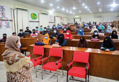 Dhaka University students wearing face masks attend their class 