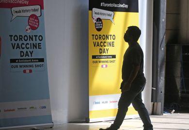 Person walks by Toronto Vaccine Day poster as metaphor for Canadian universities finally move to mandate vaccines