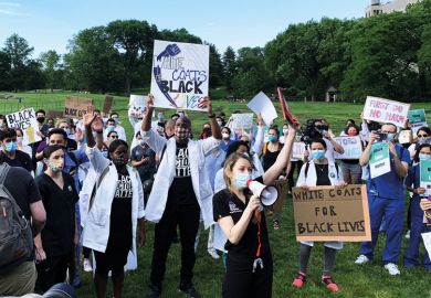 Medical workers in face masks hold signs reading White Coats for Black Lives as a metaphor for US medical schools found to be falling short on equity promises