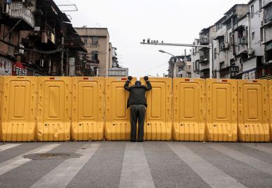 A man wearing a face mask talks to another man through a makeshift barricade wall in Wuhan, Hubei, China A man wearing a face mask talks to another man through a makeshift barricade wall in Wuhan, Hubei, China as a metaphor for China and Japan to keep borders shut for another term