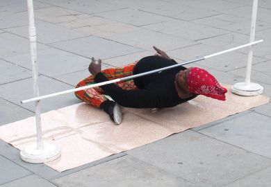 Person very low on ground under a limbo. Person very low on ground under a limbo to illustrate the University of Liverpool against making redundancies based on research grant income and citation impact scores.