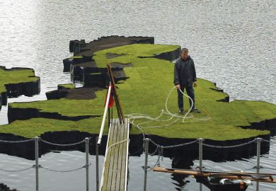 A man waters an island which has been designed in the shape of the United Kingdom to illustrate Indian Institutes of Technology set to open UK branches