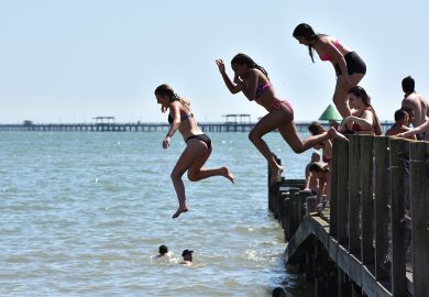 People jumping from a jetty into the sea in Southend-on-Sea, England illustrate Value of domestic students almost halves at some UK universities