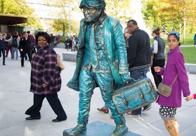 People interact with a living statue artist holing a suitcase to illustrate UK Horizon association ‘dither’ risks ‘more lost science funding’