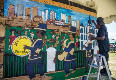 Artist painting a mural of the New Orleans Jazz and Heritage Festival to illustrate Tulane institute aims to help New Orleans ‘resurrect jobs pipeline’