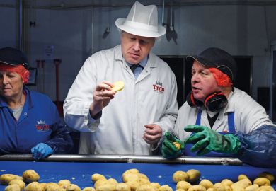 Boris Johnson checks a potato for quality with the control staff to illustrate English student number caps ‘set to use new outcomes measures’