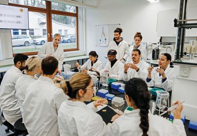 A group of students and a medical tutor working on a DNA experiment together to illustrate Team research pilot tackles dominance of principal investigators