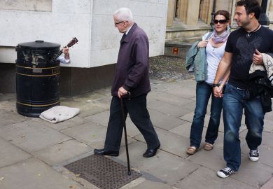 A street busker hides in a litter bin to illustrate Professor to sue Cambridge over ‘forced retirement’ rules