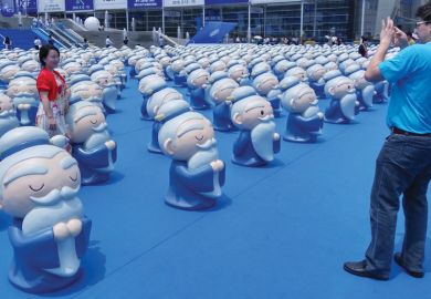 Person standing with a confucius display having her photo taken. Person standing with a confucius display as a metaphor for Germany too dependent on Confucius Institutes