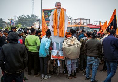 Devotees gather near an effigy of Indian prime minister Narendra Modi at the Ram Mandir Temple to illustrate Political attacks on Indian HEIs must end