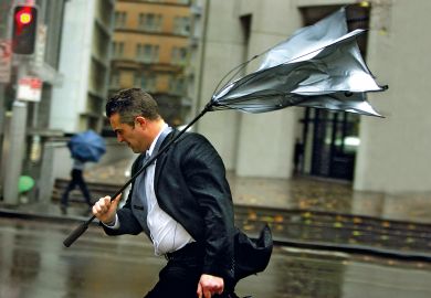 A man's umbrella turns inside-out as he battles strong winds and rain in Sydney to illustrate Rich prosper Down Under