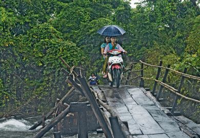 Two people ride on a motorbike across the wooden bridge in the Karen State, Myanmar to illustrate No education ‘better than oppressive one’ for Myanmar students 