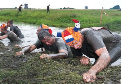 Participants of the traditional mud marathon in Schermerhornon pulling themselves up out of the water Participants of the traditional mud marathon in Schermerhornon pulling themselves up as a metaphor for recognising “team spirit”