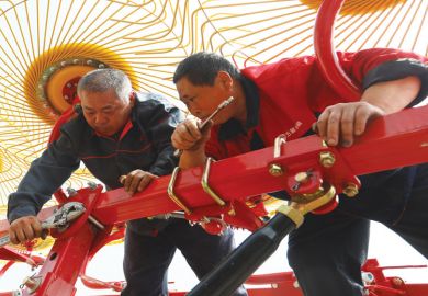 Equipment technicians repair a wheel rake in a field in China as a metaphor for overseas students fear losing degrees as China borders stay shut