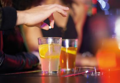 Closeup shot of a hand putting a tablet into a drink  to illustrate Freshers’ Week’s drink spiking  is not only security’s problem