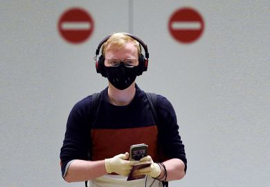 A passenger wearing PPE with two no entry signs behind him.