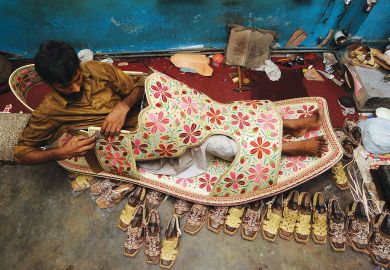 A Pakistani shoe maker, Hameed, sits inside a giant shoe at his shop in Lahore. A Pakistani shoe maker, Hameed, sits inside a giant shoe at his shop in Lahore.