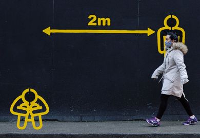 Woman walks by 2metres apart sign with diagram of person sitting down as a metaphor for Will Covid reset  the help given to deprived students.