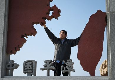 A man poses in a sculpture depicting Taiwan (R) and mainland China (L) to illustrate Cross-strait tensions hamper Chinese recruitment drive in Taiwan