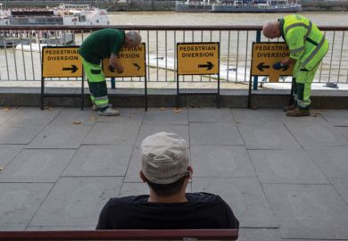 Workmen adjusting diversion arrows signs to illustrate ‘Mixed messages’ on face coverings on campus ‘harms compliance’
