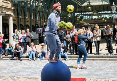 Street performer entertaining people balancing on a ball in Covent Garden Piazza Street performer entertaining people balancing on a ball  in Covent Garden Piazza to illustrate Russell Group draws majority of fee income from overseas