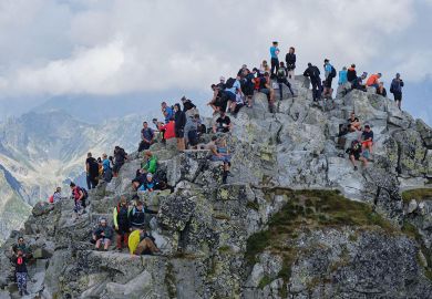Crowd of tourists, hikers, on the narrow and rocky Rysy Peak (2500m), the highest peak in Poland to illustrate Success recast as failure 