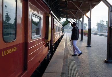 Train conductor giving wave with a green flag at Colombo fort train station. Train conductor giving wave with a green flag at Colombo fort train station to illustrate Professor departs South Asian University after Modi criticism row