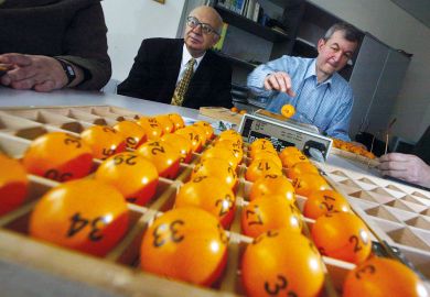 An official prepares lottery balls to illustrate British Academy trials awarding research grants by lottery