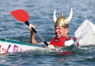Person wearing viking hat in a cardboard boat sinking at a boat Regatta Person wearing viking hat in a cardboard boat sinking at a boat Regatta to illustrate the Danish humanities courses pressed on contact hours as funding cut