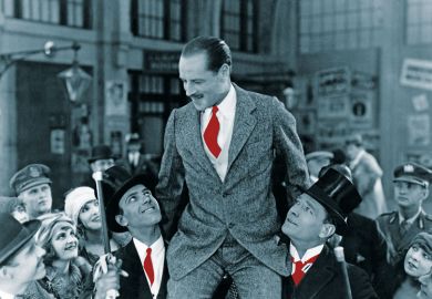 Man carried on shoulders above crowd to illustrate Who’s a jolly good fellow?