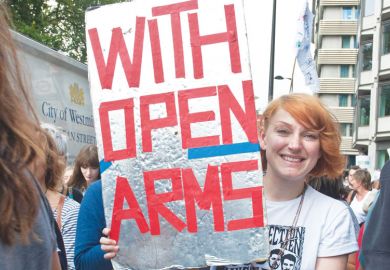 Person in a refugee demonstration London UK holding a banner reading 'With Open Arms' Person in a refugee demonstration London UK holding a banner reading 'With Open Arms'