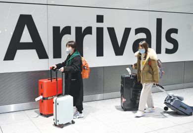 Chinese passengers wear face masks as the push their luggage after arriving from a flight at Terminal 5 of London Heathrow Airport 