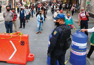 Police and city government workers stand at a pedestrian control that limits the access in groups of 20 people to enter downtown Mexico City 
