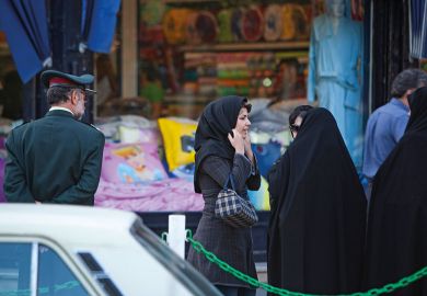 An Iranian woman adjusts her scarf as two veiled morality policewomen talk to them in Tehran An Iranian woman adjusts her scarf as two veiled morality policewomen talk to them in Tehran to illustrate Iranian scholar who resigned in protest may need to seek asylum