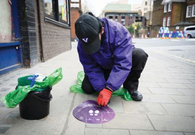 Person removes social distancing sticker as a metaphor for returning to university as will be able to reopen