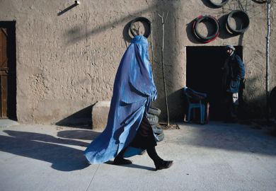 A woman wearing a burqa walks along a road at the Khwaja Koza Gar area in Herat to illustrate Segregation and half-empty campuses as Afghan universities reopen