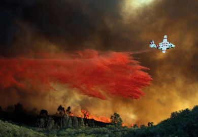 An airplane makes a fire retardant drop on a large hill-top home