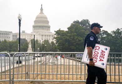 A U.S. Capitol police officer carries "Area Closed" signs in front of the U.S. Capitol  to illustrate Could US education department be shut?